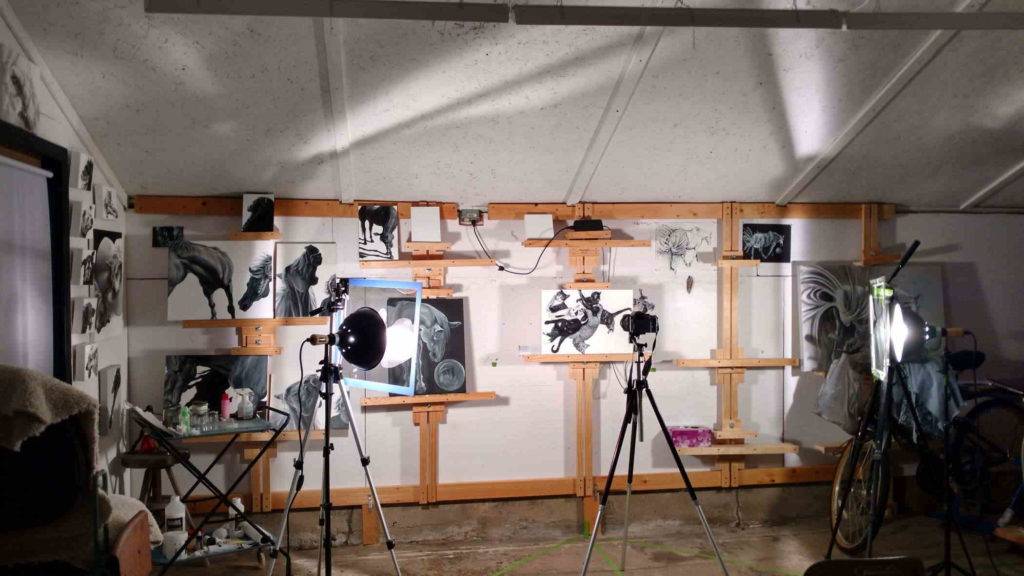 a photo shoot on the easel wall featuring Cat Pile Up, 2019, shows photo lights in otherwise darkened room..