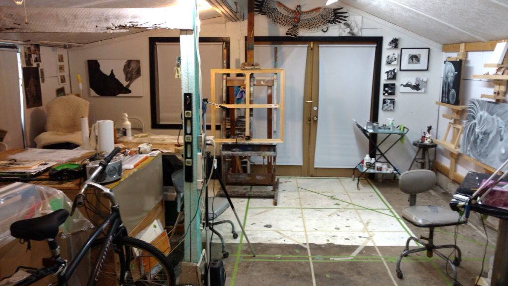 a view of the front room of the studio now largely painted white with some canvases in view and shades drawn on interior and exterior windows.