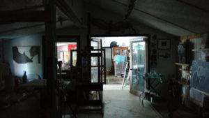 a view from the darkened front of the studio through the window and open doors of the dividing wall into the naturally lit back room