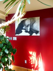 painting cat shadows installed on a red wall with a green plant in the foreground